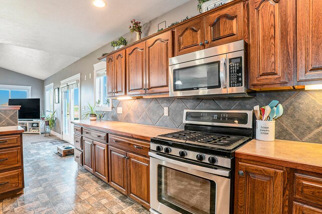 kitchen featuring appliances with stainless steel finishes, vaulted ceiling, and decorative backsplash