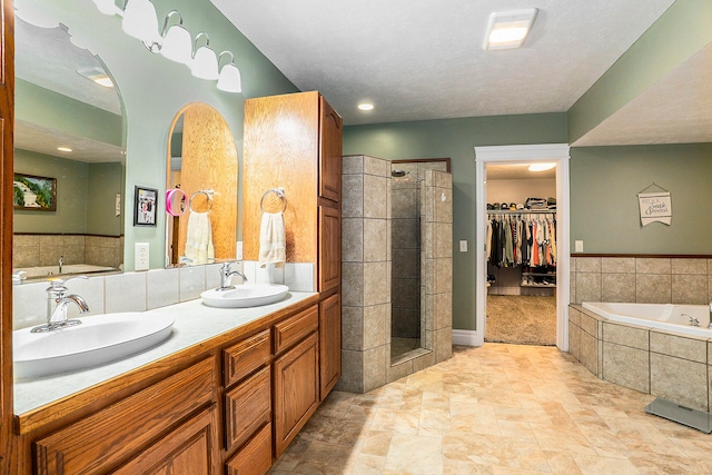 bathroom featuring a textured ceiling, shower with separate bathtub, and vanity