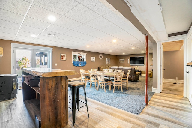 dining room with french doors, a wood stove, hardwood / wood-style floors, and a paneled ceiling