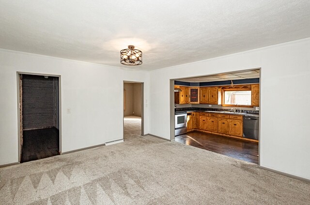 unfurnished living room with a textured ceiling, baseboard heating, dark colored carpet, and sink