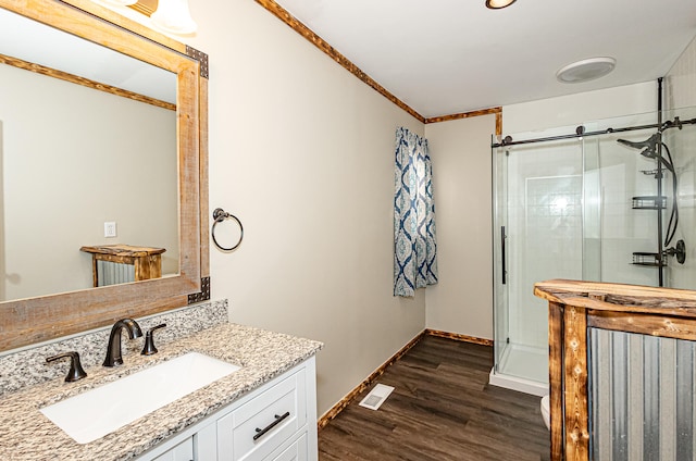 bathroom with hardwood / wood-style flooring, vanity, ornamental molding, and an enclosed shower