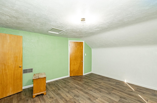 bonus room with a textured ceiling, vaulted ceiling, and dark wood-type flooring