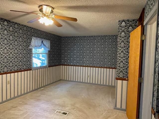 carpeted spare room with a textured ceiling and ceiling fan