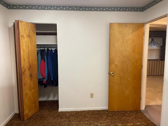 unfurnished bedroom featuring a closet and dark carpet