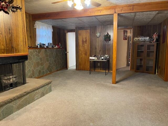 basement with wooden walls, carpet flooring, and ceiling fan