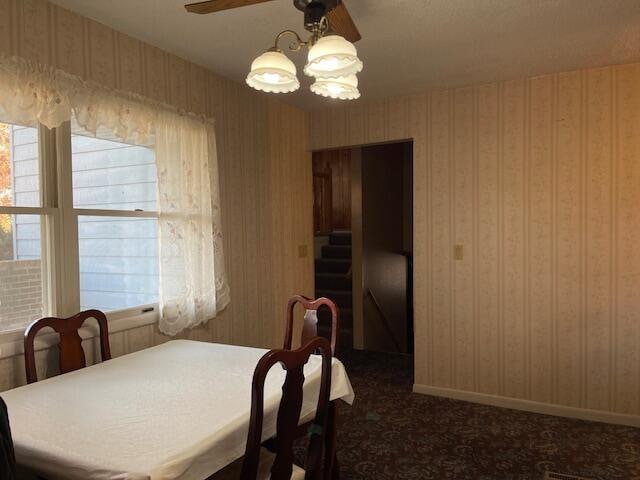 dining area with dark colored carpet and ceiling fan