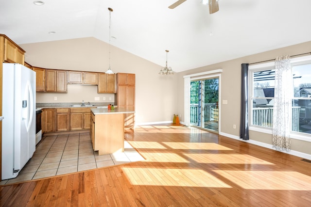 kitchen with white fridge with ice dispenser, a center island, light hardwood / wood-style flooring, vaulted ceiling, and decorative light fixtures