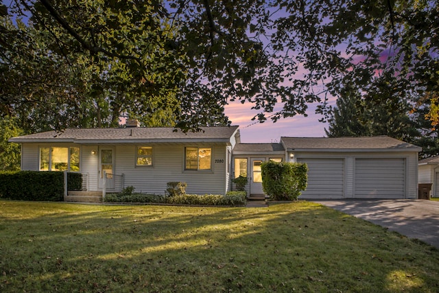 ranch-style house featuring a garage and a lawn