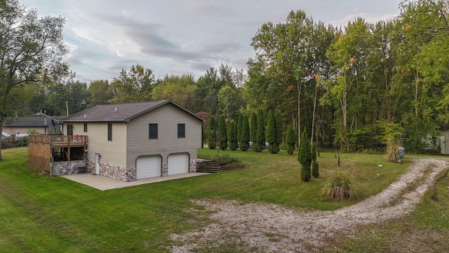 rear view of property with a deck, a yard, and a garage