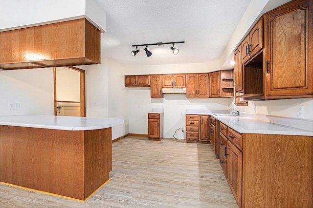 kitchen featuring kitchen peninsula, a textured ceiling, light hardwood / wood-style flooring, and sink