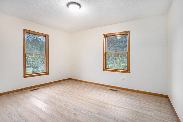 empty room with light hardwood / wood-style floors and a textured ceiling