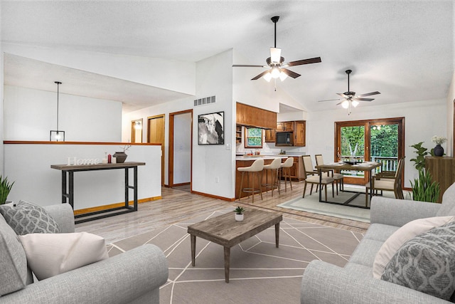 living room with lofted ceiling, ceiling fan, and light hardwood / wood-style floors