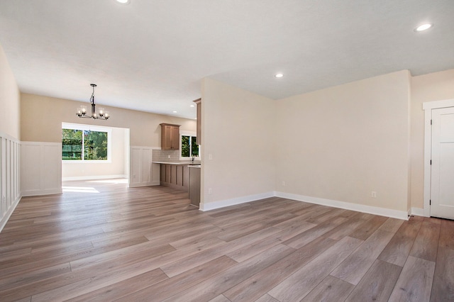 unfurnished living room with a notable chandelier and light hardwood / wood-style flooring