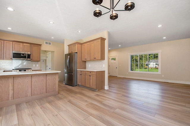 kitchen with stainless steel appliances, an inviting chandelier, decorative backsplash, and light hardwood / wood-style flooring