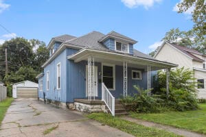 bungalow-style house featuring covered porch, an outbuilding, and a garage