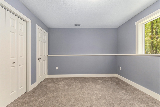 unfurnished bedroom with a textured ceiling, carpet, and a closet