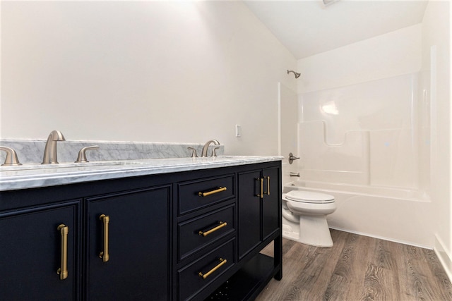 full bathroom with lofted ceiling, bathing tub / shower combination, hardwood / wood-style floors, vanity, and toilet