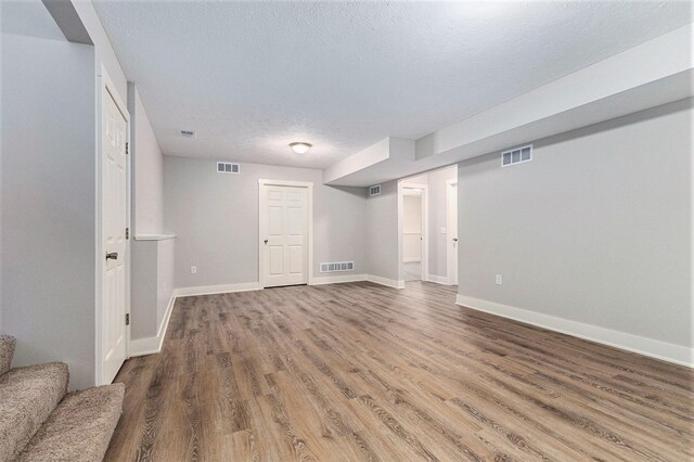 basement featuring hardwood / wood-style flooring and a textured ceiling