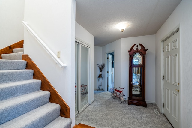 carpeted entrance foyer with a textured ceiling