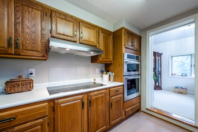 kitchen featuring a textured ceiling, double oven, light colored carpet, and electric cooktop