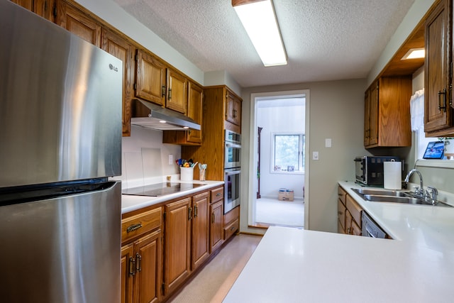 kitchen with a textured ceiling, stainless steel appliances, and sink