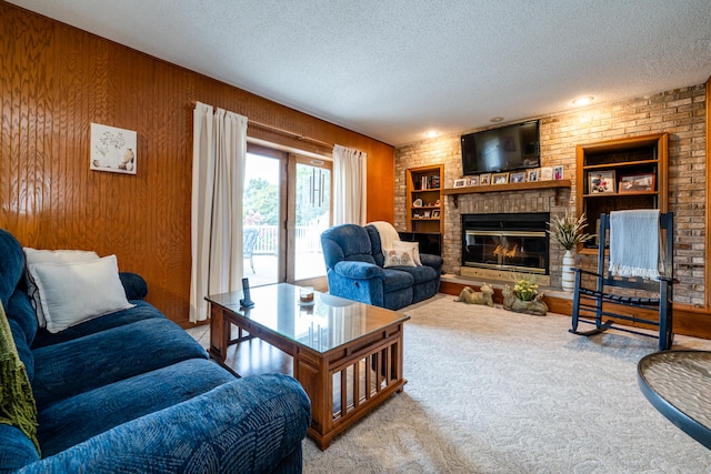 living room with a textured ceiling, wooden walls, carpet flooring, and a fireplace