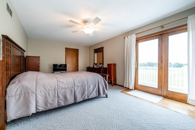 bedroom with light wood-type flooring, ceiling fan, access to exterior, and a textured ceiling