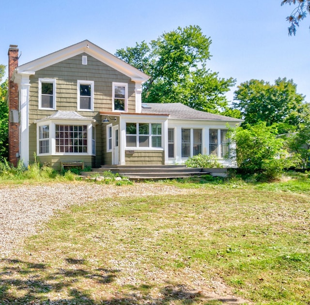 rear view of property with a yard and a sunroom