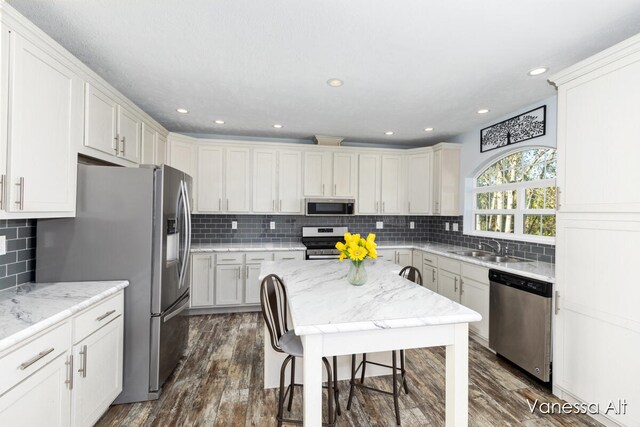 kitchen featuring stainless steel appliances, sink, white cabinetry, tasteful backsplash, and dark wood-type flooring