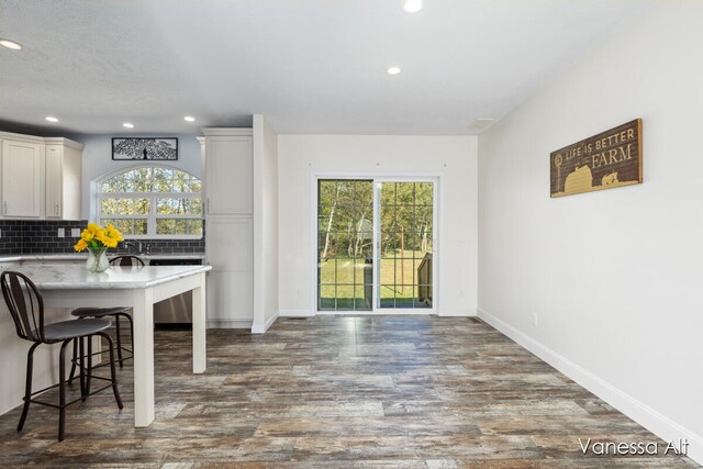 kitchen with a breakfast bar area, white cabinetry, tasteful backsplash, and dark hardwood / wood-style floors