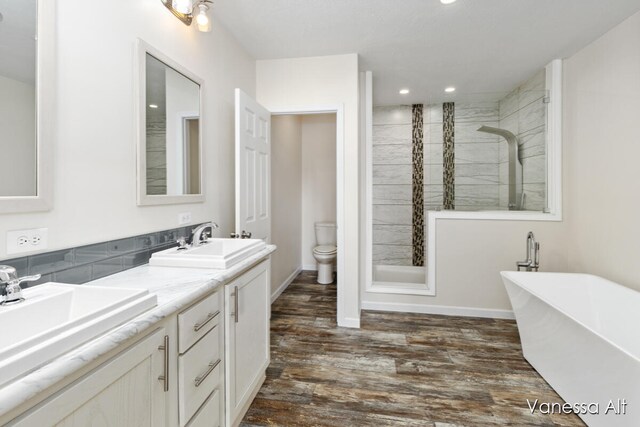 full bathroom featuring toilet, hardwood / wood-style flooring, independent shower and bath, and vanity