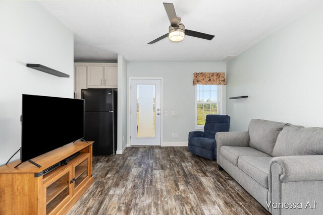 living room featuring ceiling fan and dark wood-type flooring