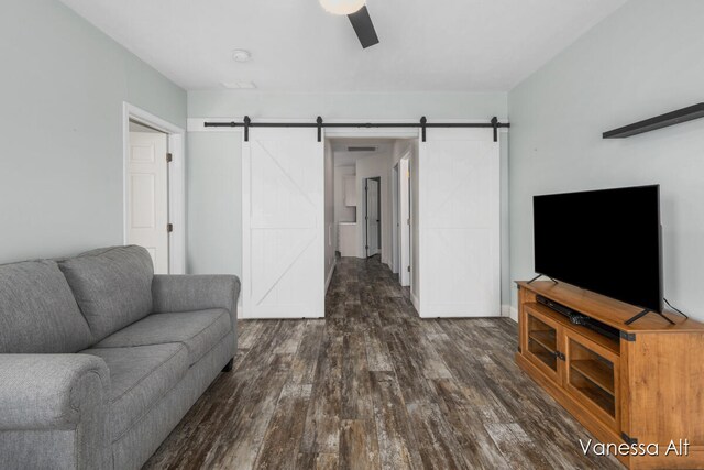 living room with ceiling fan, dark hardwood / wood-style flooring, and a barn door