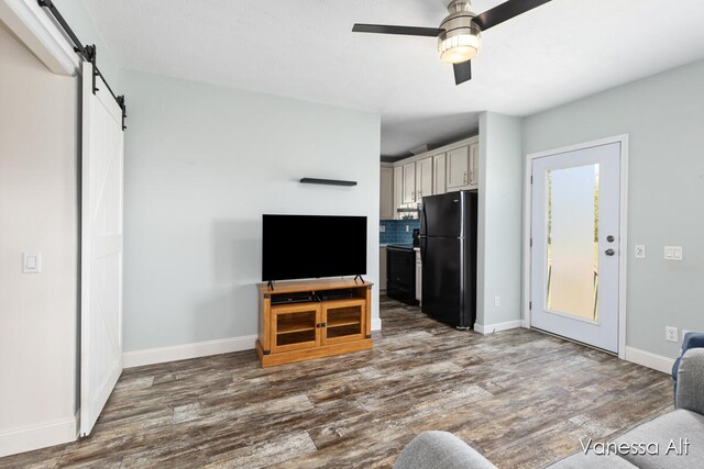 living room with ceiling fan, dark wood-type flooring, and a barn door