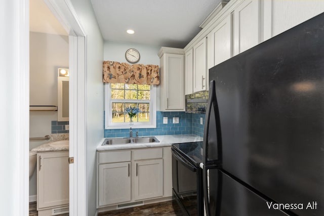 kitchen featuring sink, white cabinets, decorative backsplash, black appliances, and dark wood-type flooring