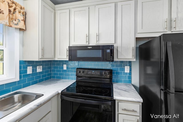 kitchen with sink, white cabinetry, light stone counters, backsplash, and black appliances