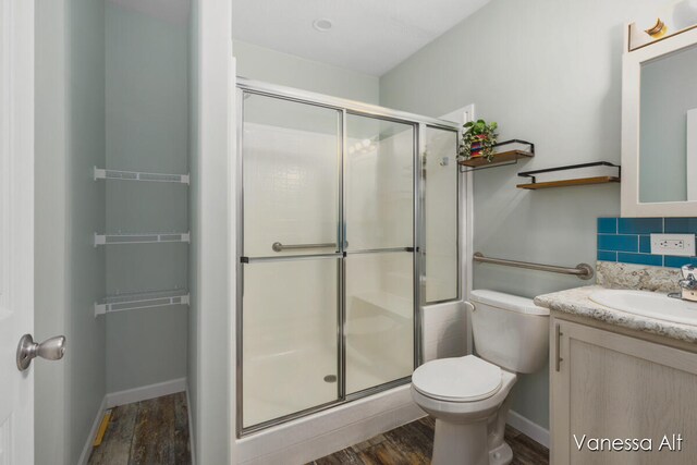 bathroom featuring vanity, wood-type flooring, walk in shower, and tasteful backsplash