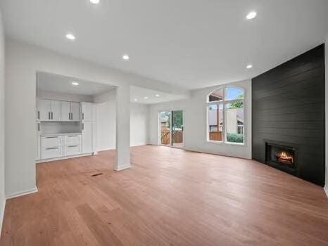 unfurnished living room featuring light wood-type flooring and a large fireplace