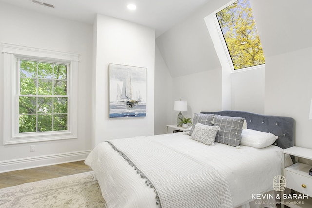 bedroom with lofted ceiling, wood-type flooring, and multiple windows