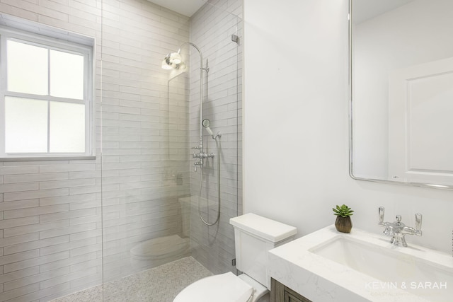 bathroom with vanity, a tile shower, and toilet