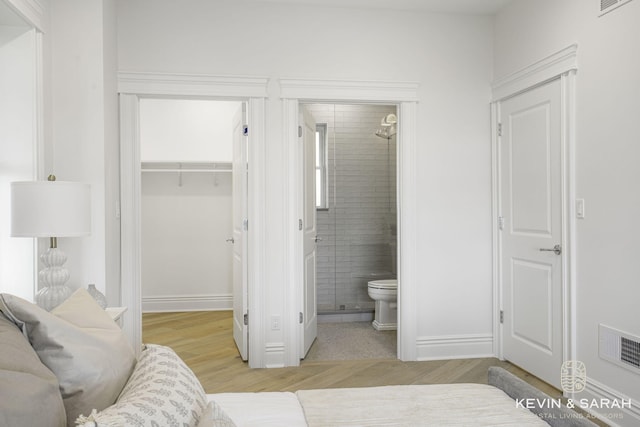 bathroom with toilet, a tile shower, and wood-type flooring