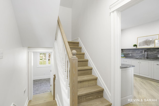 staircase with wood-type flooring and sink