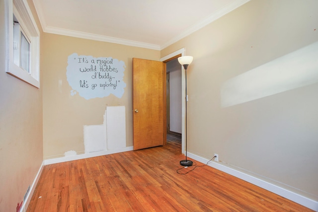 empty room with hardwood / wood-style flooring and crown molding