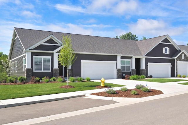 craftsman inspired home with a garage and a front lawn