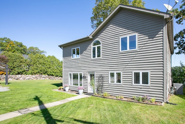 rear view of property featuring cooling unit and a lawn