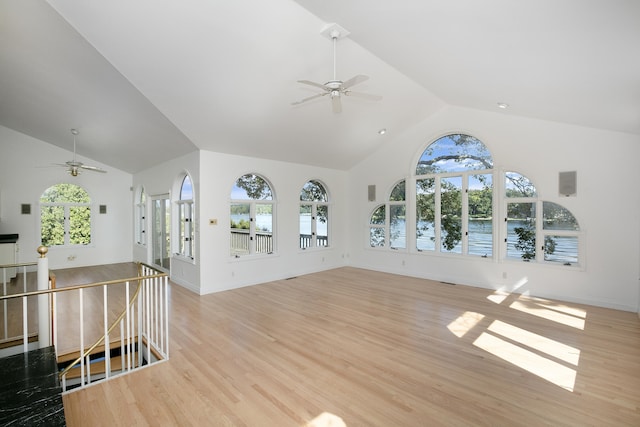 unfurnished living room featuring ceiling fan, lofted ceiling, light hardwood / wood-style floors, and a healthy amount of sunlight