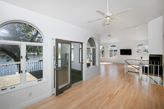 interior space with ceiling fan, lofted ceiling, light wood-type flooring, and a water view