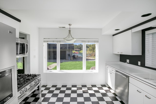 kitchen featuring white cabinets, appliances with stainless steel finishes, and pendant lighting