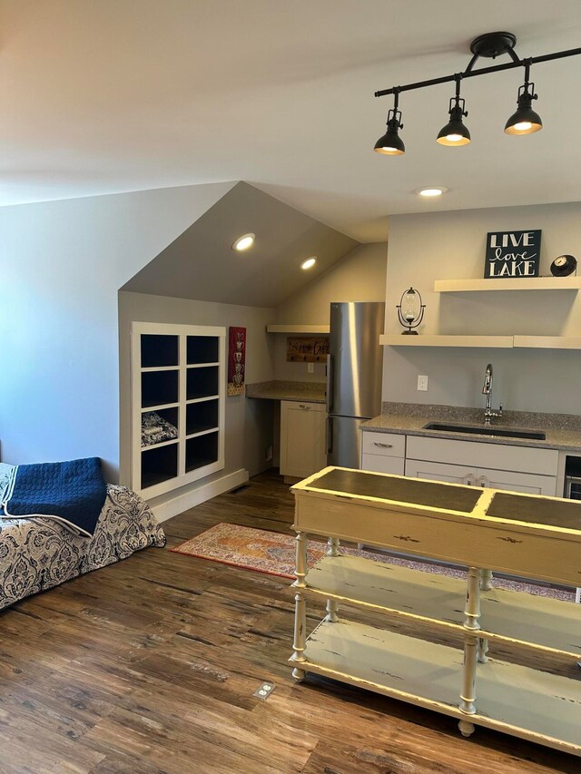 kitchen with dark hardwood / wood-style floors, sink, vaulted ceiling, hanging light fixtures, and stainless steel refrigerator