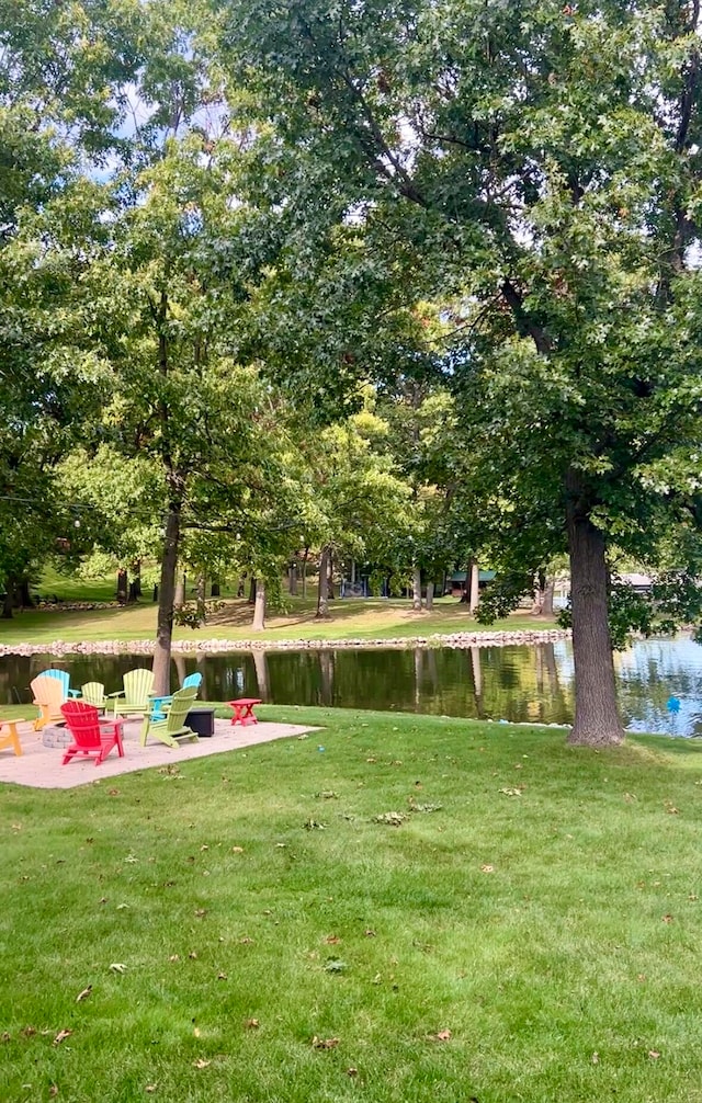 surrounding community with a lawn, a water view, and a patio area